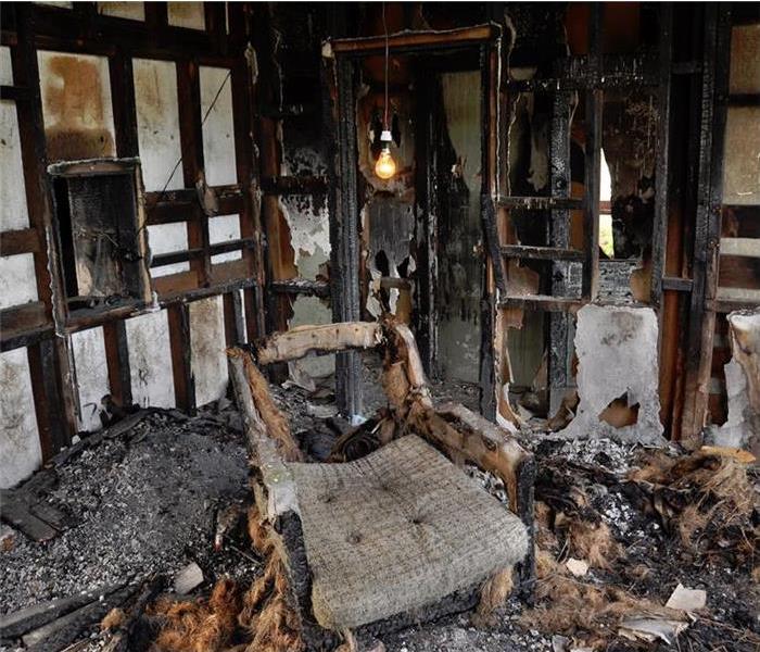 inside of home, chair in middle of the room, everything completely burnt. Debris everywhere